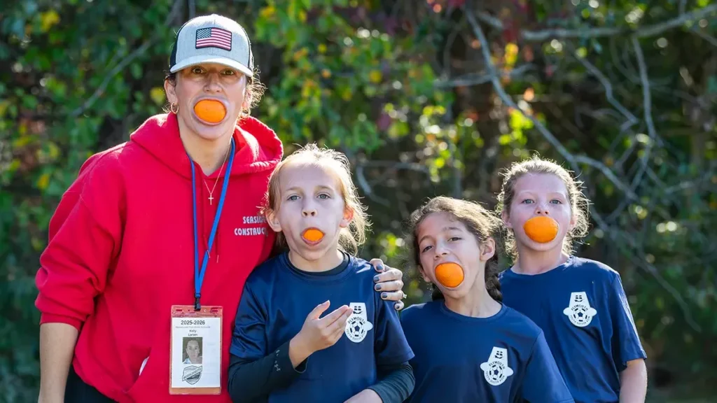 PYSA Developmental Girls and their coach with oranges in their mouths